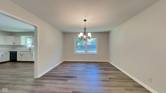 unfurnished dining area featuring light hardwood / wood-style flooring, sink, and a notable chandelier