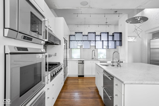 kitchen with white cabinets, sink, a center island with sink, dark wood-type flooring, and stainless steel appliances