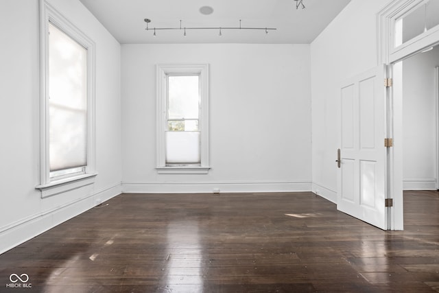 empty room with rail lighting and dark hardwood / wood-style flooring