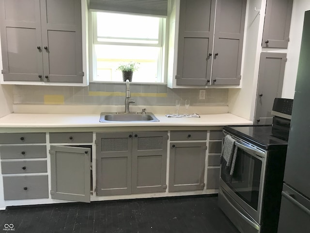 kitchen with gray cabinetry, decorative backsplash, stainless steel range with electric stovetop, and sink