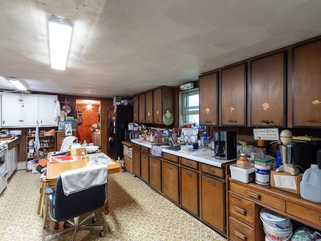 kitchen featuring dark brown cabinetry, black fridge, and stainless steel stove