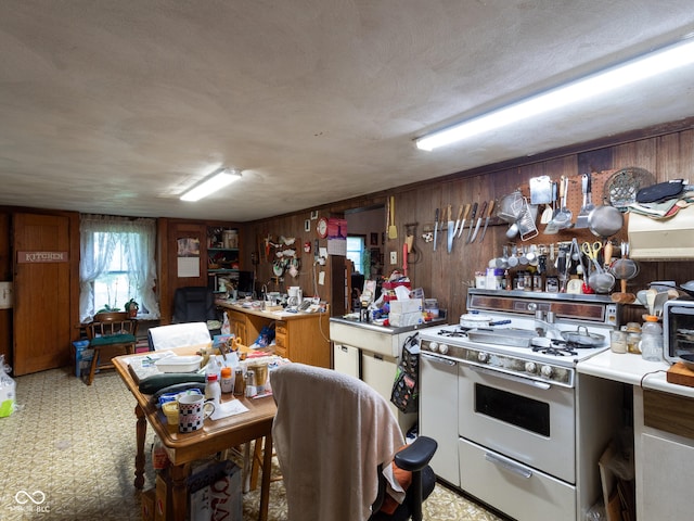 kitchen featuring white range, a textured ceiling, and wooden walls