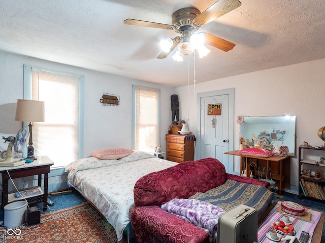 bedroom with ceiling fan, a textured ceiling, and multiple windows