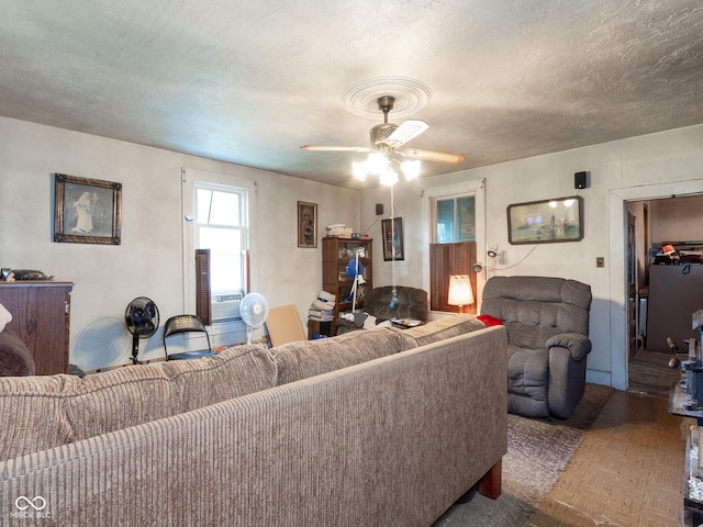 living room featuring ceiling fan, a textured ceiling, and parquet flooring