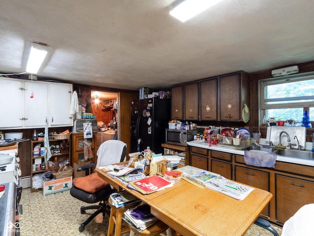 kitchen with dark brown cabinets, black fridge, and sink