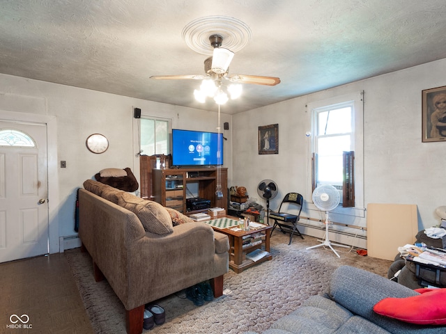 living room with a baseboard heating unit, ceiling fan, and a textured ceiling