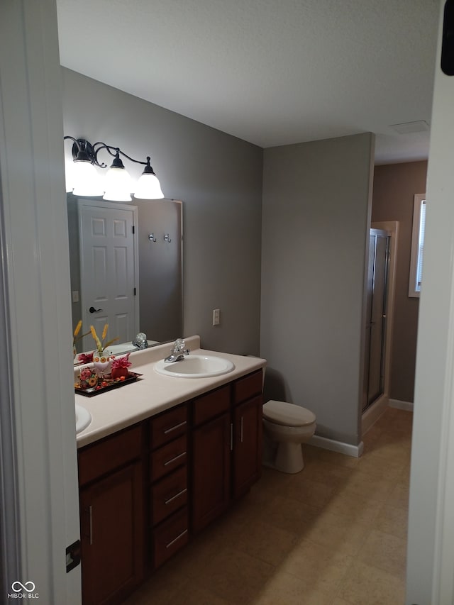 bathroom featuring toilet, vanity, and a shower with shower door