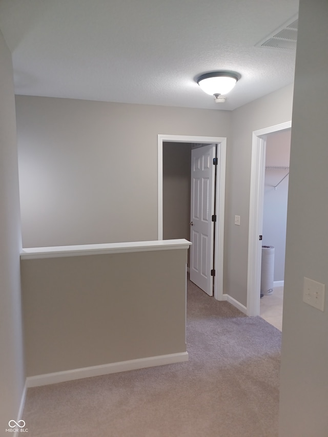 hallway featuring a textured ceiling and light colored carpet