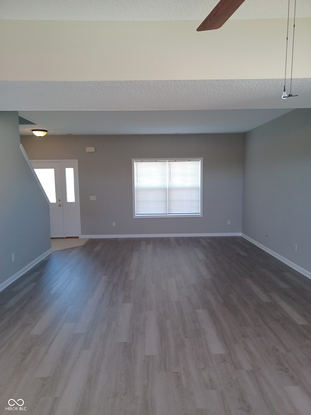 unfurnished living room featuring hardwood / wood-style floors, ceiling fan, and a textured ceiling