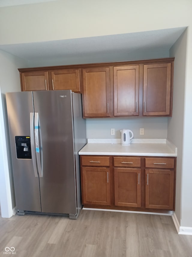 kitchen with stainless steel fridge with ice dispenser and light wood-type flooring