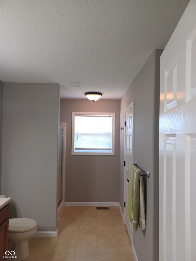 bathroom featuring an enclosed shower, vanity, a textured ceiling, and toilet