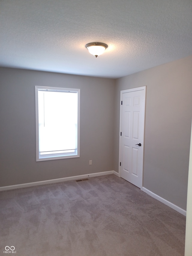 carpeted spare room with a textured ceiling