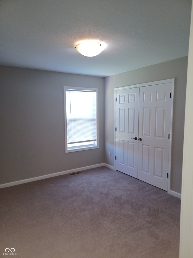 unfurnished bedroom featuring carpet flooring, a textured ceiling, and a closet