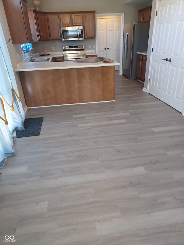 kitchen featuring kitchen peninsula, stainless steel appliances, and light wood-type flooring