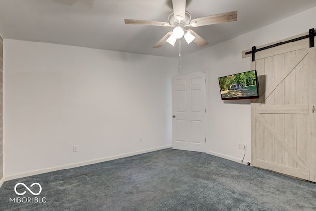 carpeted spare room featuring a barn door and ceiling fan