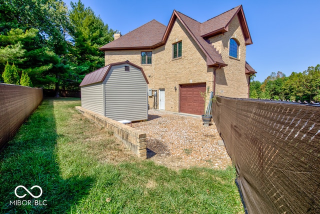 rear view of house featuring a yard, a garage, and a storage unit