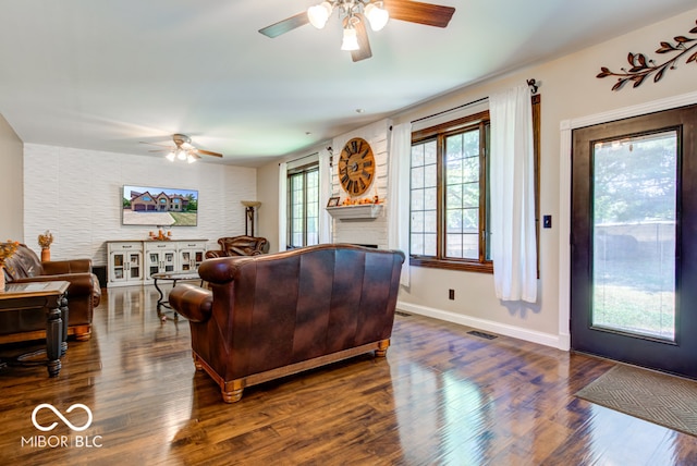 living room with a brick fireplace, dark hardwood / wood-style floors, and ceiling fan