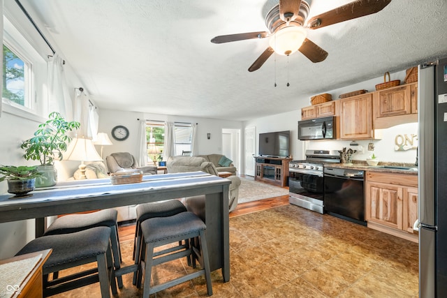 kitchen with a breakfast bar, black appliances, ceiling fan, and a textured ceiling