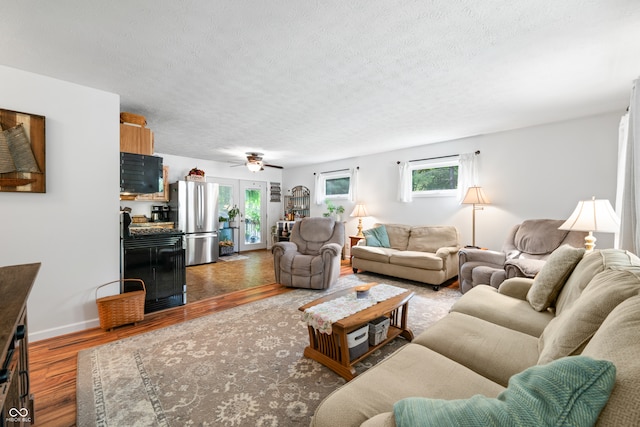 living room featuring a textured ceiling, hardwood / wood-style floors, and ceiling fan