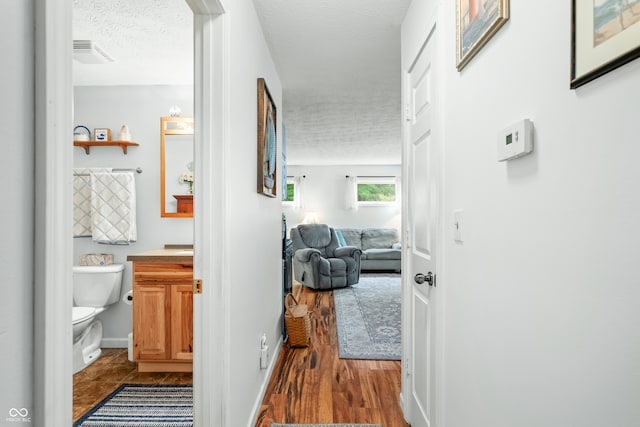 corridor with a textured ceiling and hardwood / wood-style floors