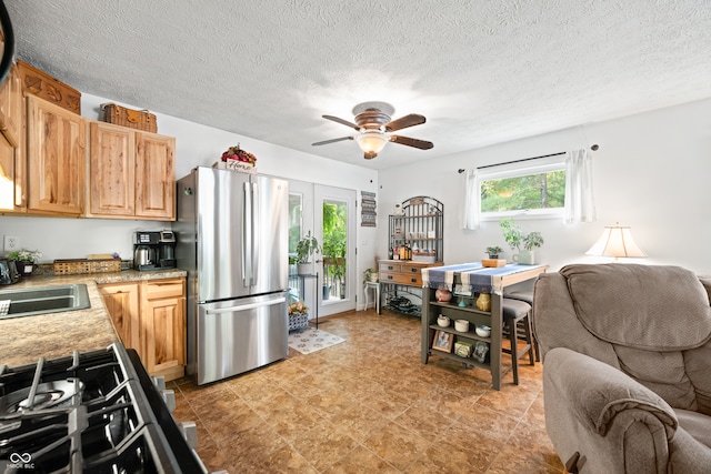 kitchen with appliances with stainless steel finishes, a textured ceiling, light brown cabinetry, ceiling fan, and french doors