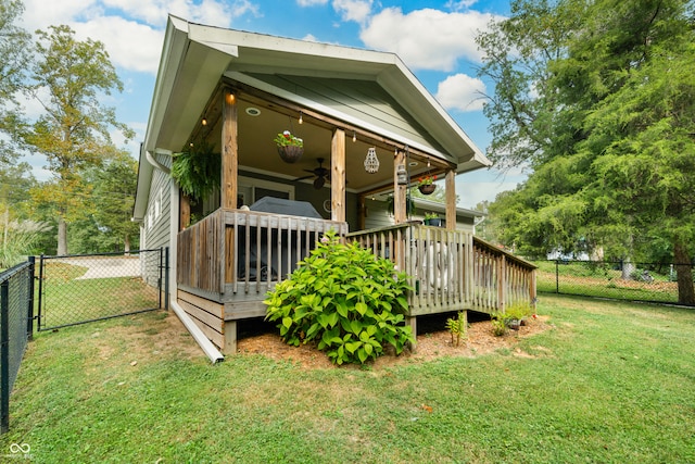 back of house featuring a lawn, ceiling fan, and a wooden deck