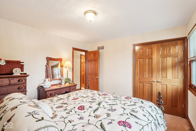 carpeted bedroom featuring a textured ceiling and a closet