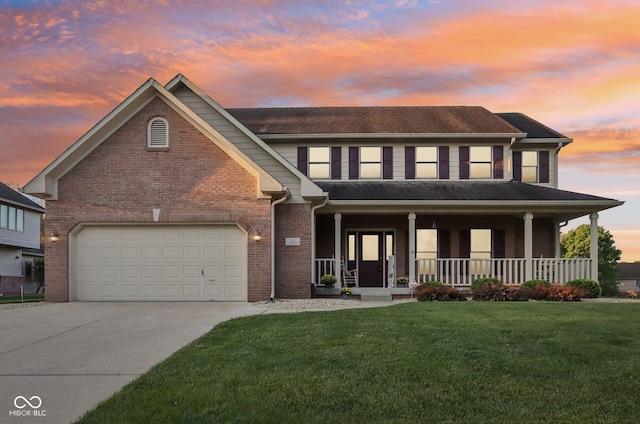 view of front facade featuring a porch, a yard, and a garage