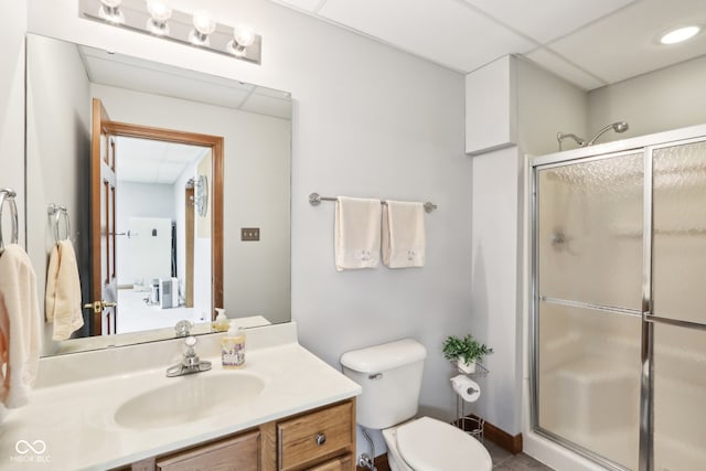 bathroom featuring a paneled ceiling, vanity, a shower with shower door, and toilet