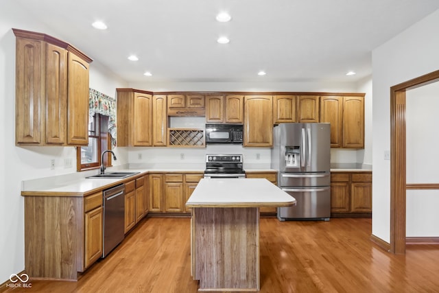 kitchen with stainless steel appliances, a kitchen island, light hardwood / wood-style floors, and sink