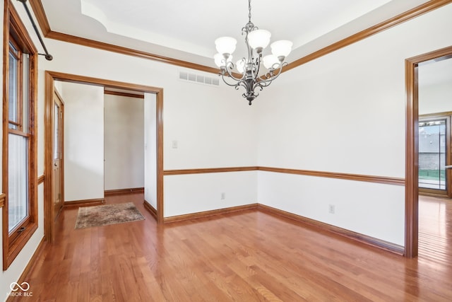 unfurnished room with hardwood / wood-style floors, an inviting chandelier, and ornamental molding