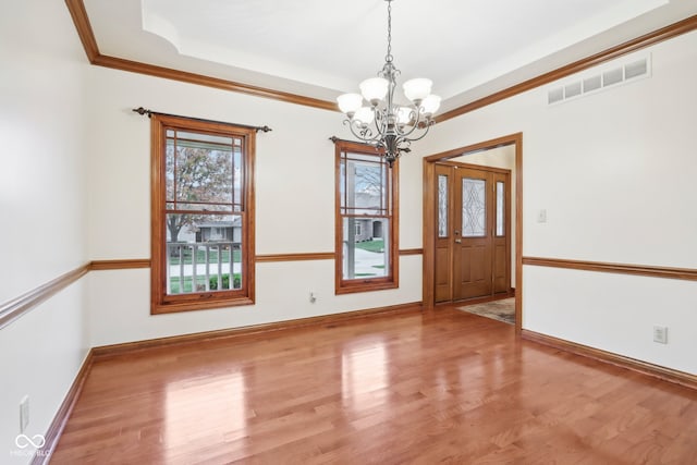 unfurnished room featuring wood-type flooring, an inviting chandelier, and ornamental molding