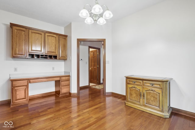 kitchen featuring a chandelier, built in desk, and hardwood / wood-style flooring