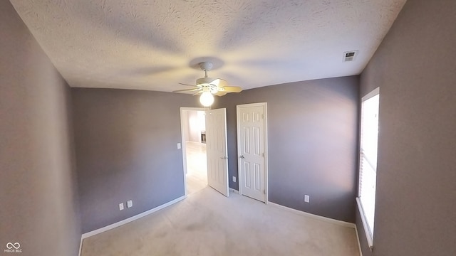 carpeted empty room featuring ceiling fan and a textured ceiling