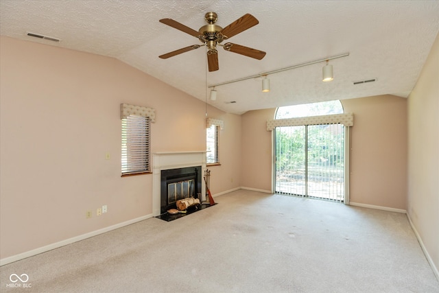 unfurnished living room featuring vaulted ceiling, carpet floors, a textured ceiling, ceiling fan, and track lighting