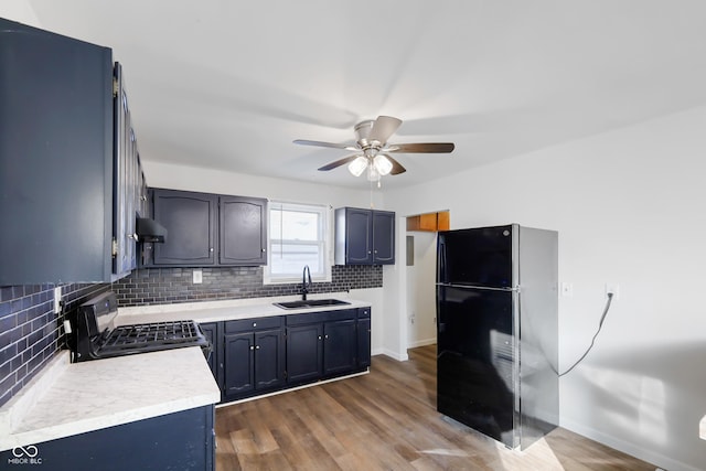 kitchen featuring sink, dark hardwood / wood-style floors, gas stove, black fridge, and decorative backsplash