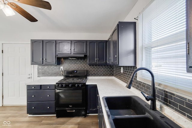 kitchen with black range with gas cooktop, sink, light hardwood / wood-style flooring, ceiling fan, and decorative backsplash