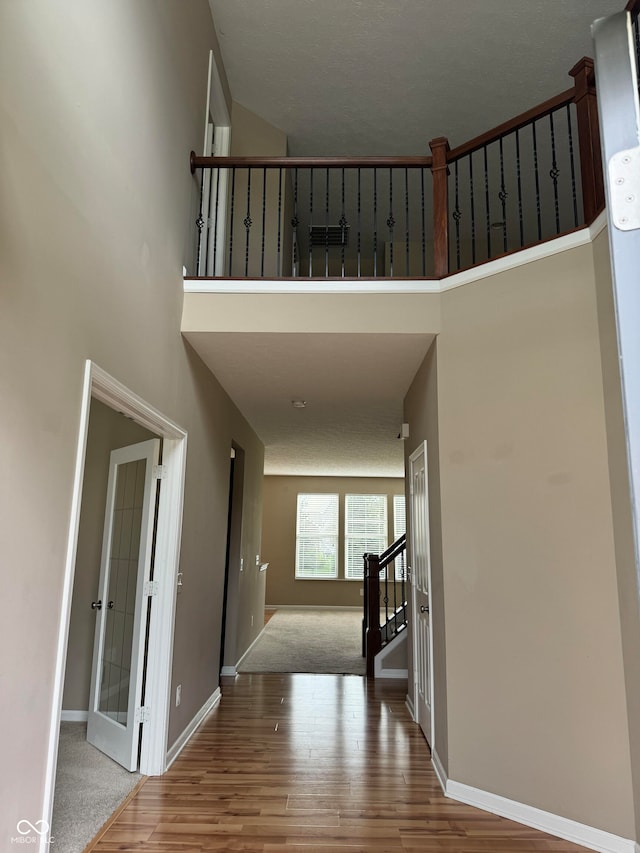 interior space with a textured ceiling, a high ceiling, and hardwood / wood-style floors