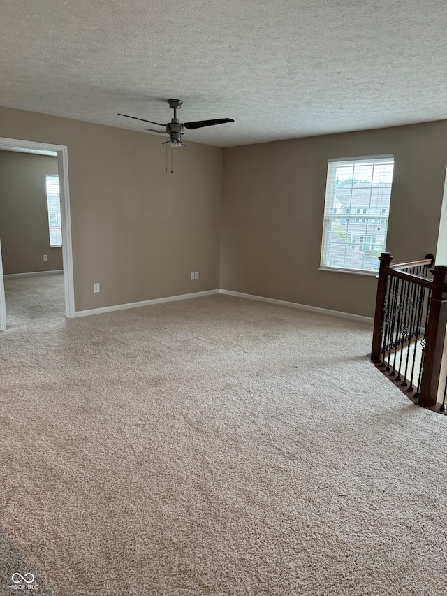 spare room with a textured ceiling, ceiling fan, and light colored carpet