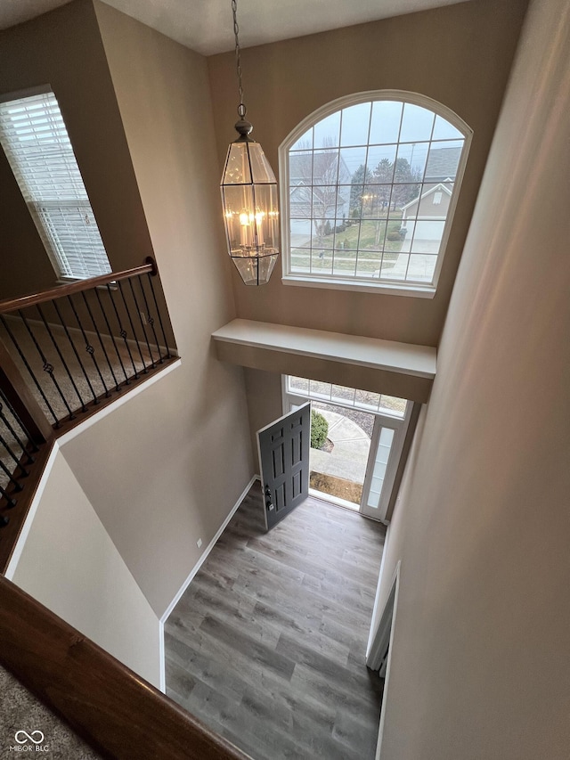 interior space with a notable chandelier, a towering ceiling, baseboards, and wood finished floors