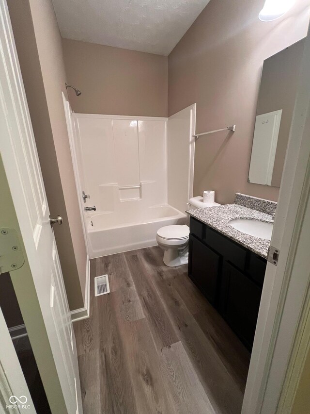 full bathroom with visible vents, toilet, vanity, shower / tub combination, and wood finished floors