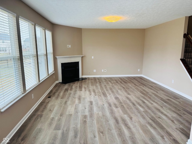 unfurnished living room with a fireplace with raised hearth, light wood-type flooring, and baseboards