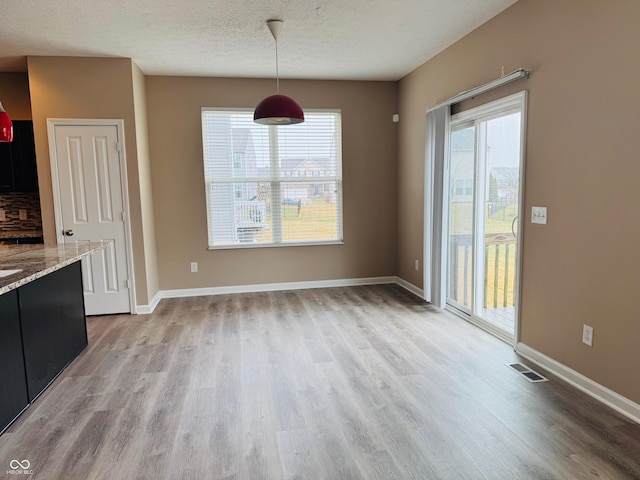 unfurnished dining area with light wood-style floors, baseboards, and visible vents