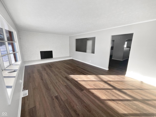 unfurnished living room with dark hardwood / wood-style flooring, a large fireplace, and a textured ceiling