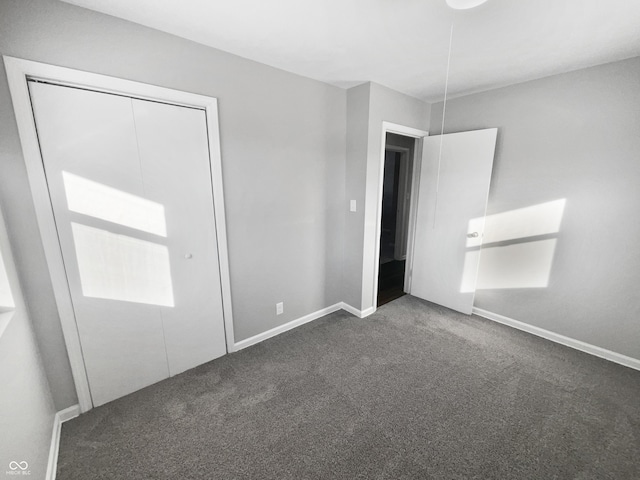 unfurnished bedroom with a closet and dark colored carpet