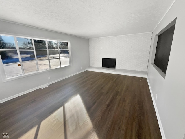 unfurnished living room featuring a textured ceiling, a brick fireplace, and hardwood / wood-style floors