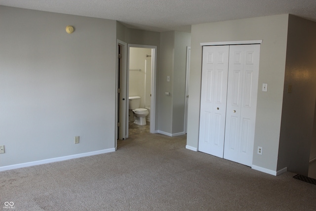 unfurnished bedroom featuring a textured ceiling, a closet, carpet floors, and ensuite bathroom