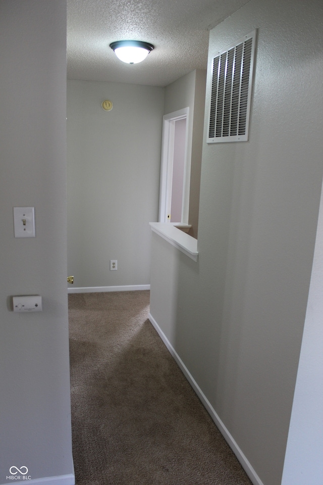 hallway with carpet floors and a textured ceiling