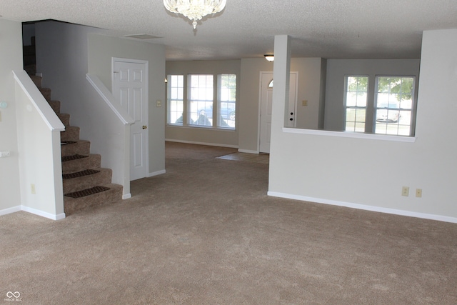 interior space with an inviting chandelier, a textured ceiling, and carpet