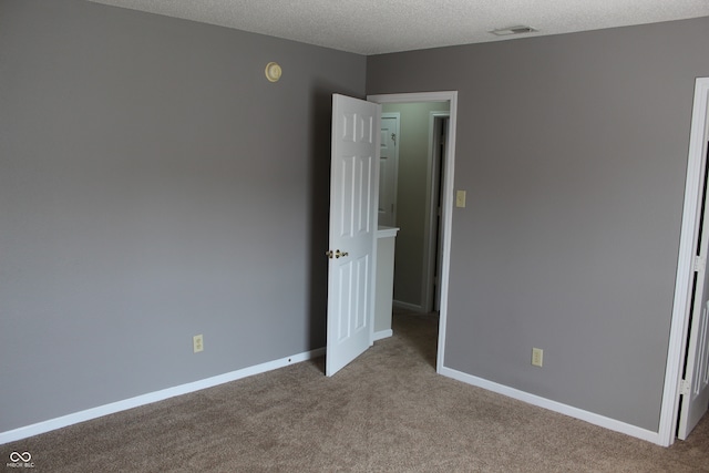 unfurnished room featuring light carpet and a textured ceiling